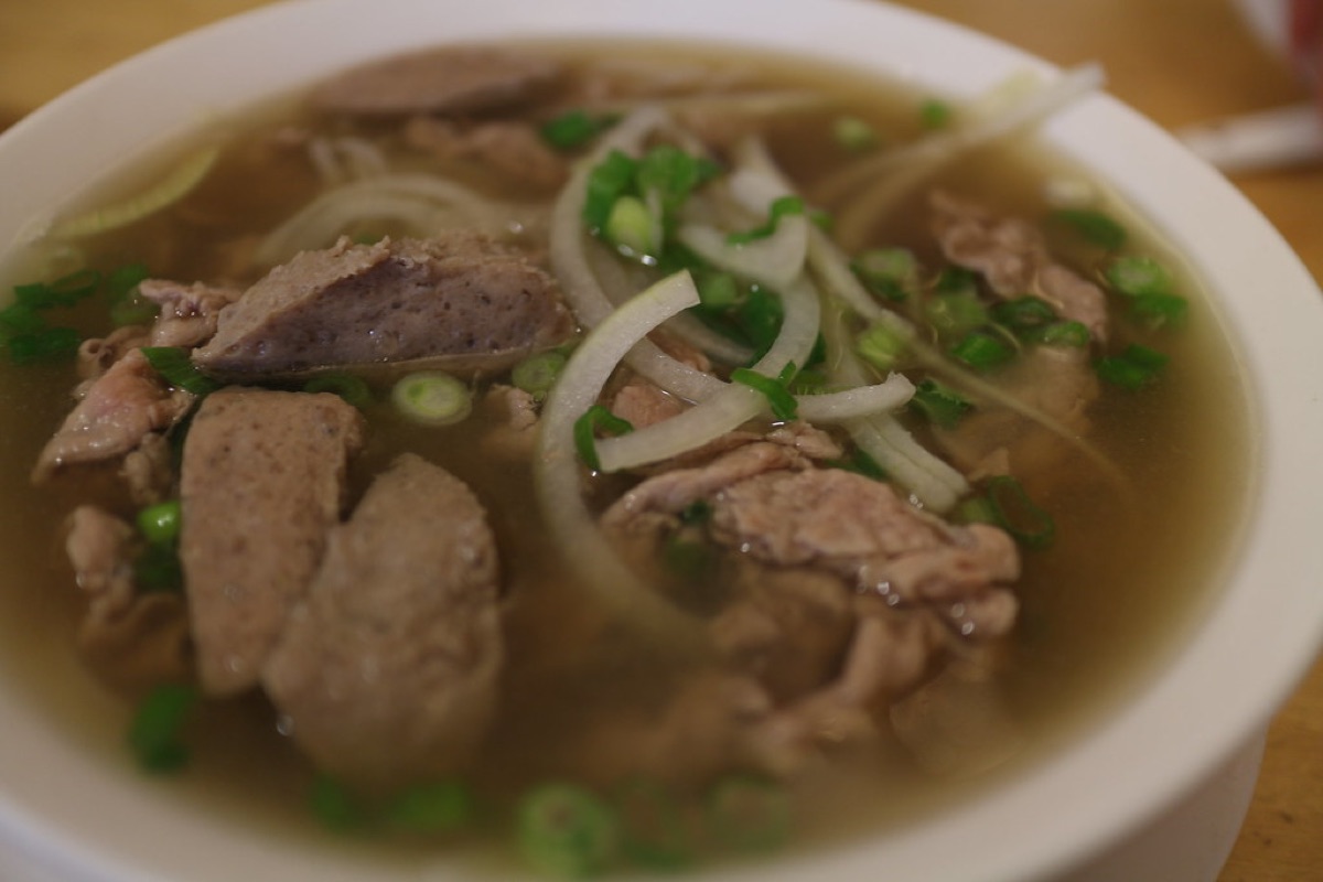 Bol de soupe Pho vietnamienne avec tranches de bœuf et herbes fraîches.