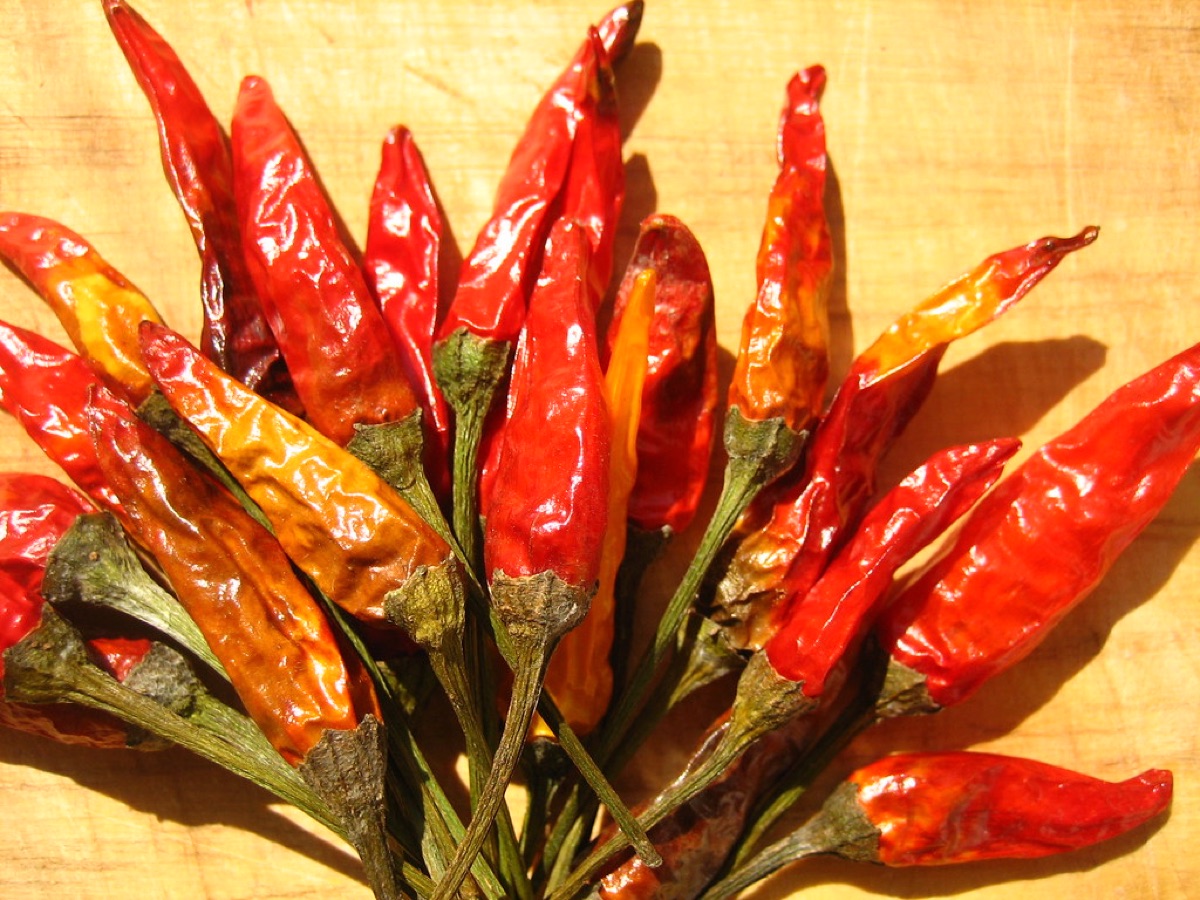 A pile of dried red chili peppers and spices on a kitchen surface.