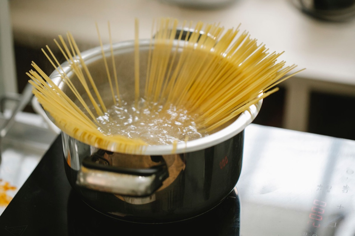 Close up of wavy ramen noodles being lifted from a boiling pot.