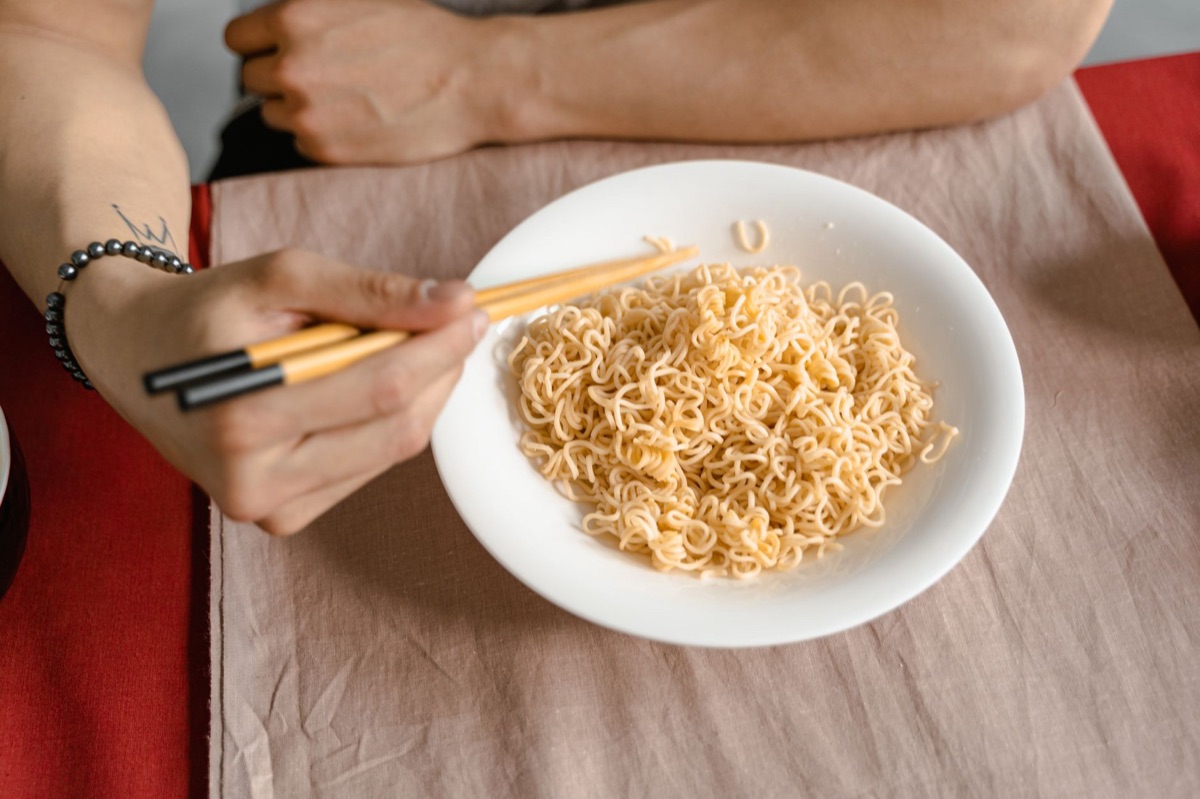 Primo piano di una persona che mangia ramen con le bacchette.