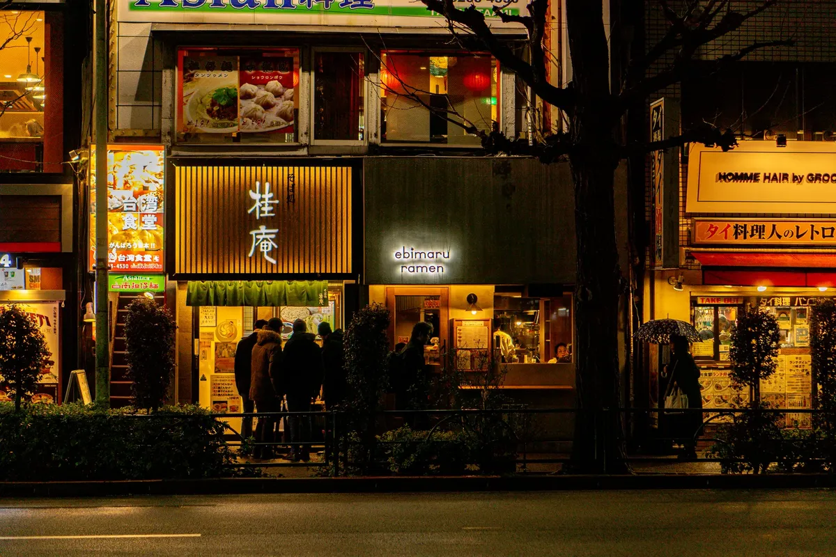 東京繁忙的街道，夜晚有照明的拉麵店和顧客。