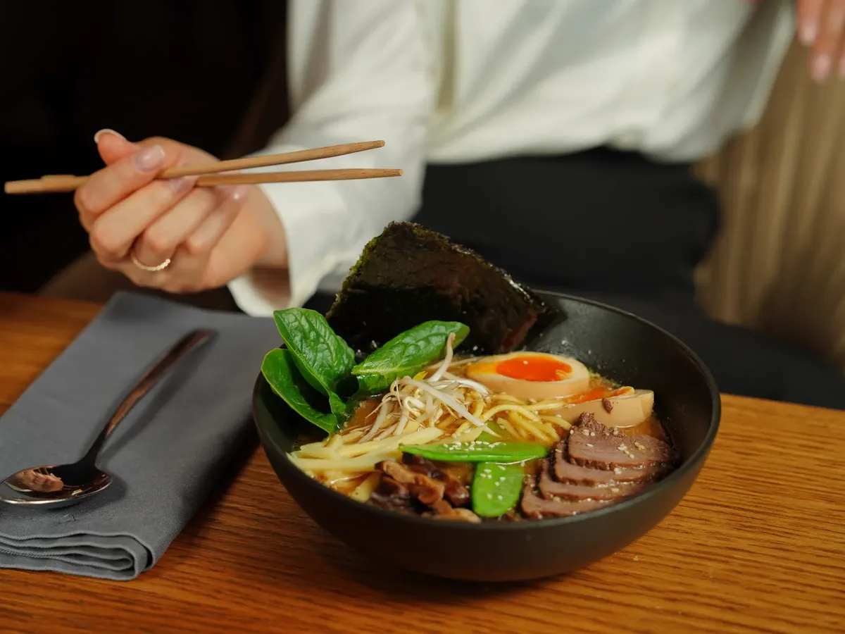 Close-up of a delicious bowl of ramen being enjoyed with chopsticks, highlighting Japanese cuisine.
