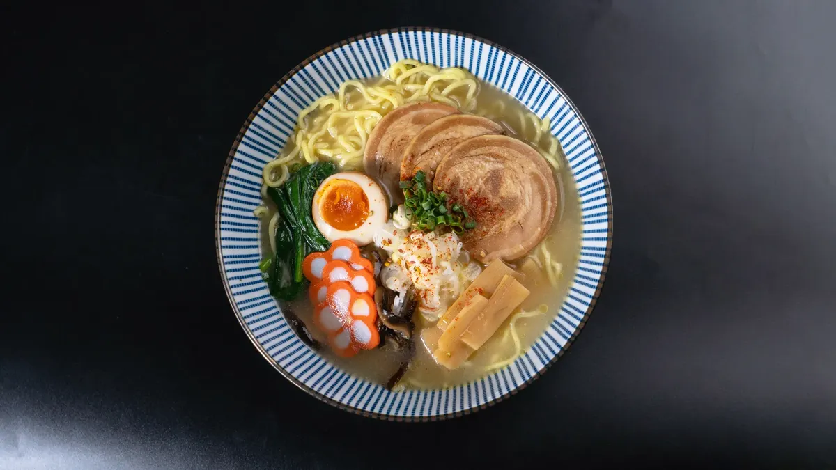 一碗香濃的拉麵配各種配料，搭配黑色背景，完美適合食物愛好者。