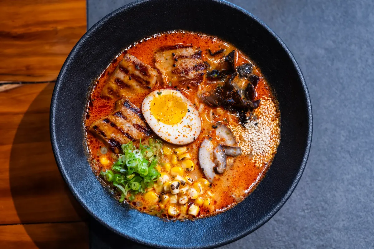 辛いラメンの美しい碗に、焼いた鸡肉、卵、そしてさまざまなトッピングが乗っています。