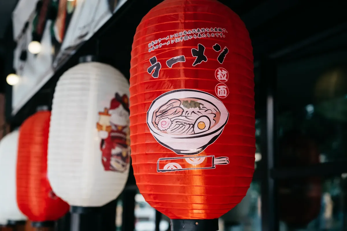 Close-up of a vibrant red lantern featuring a ramen bowl illustration in Bangkok, Thailand.